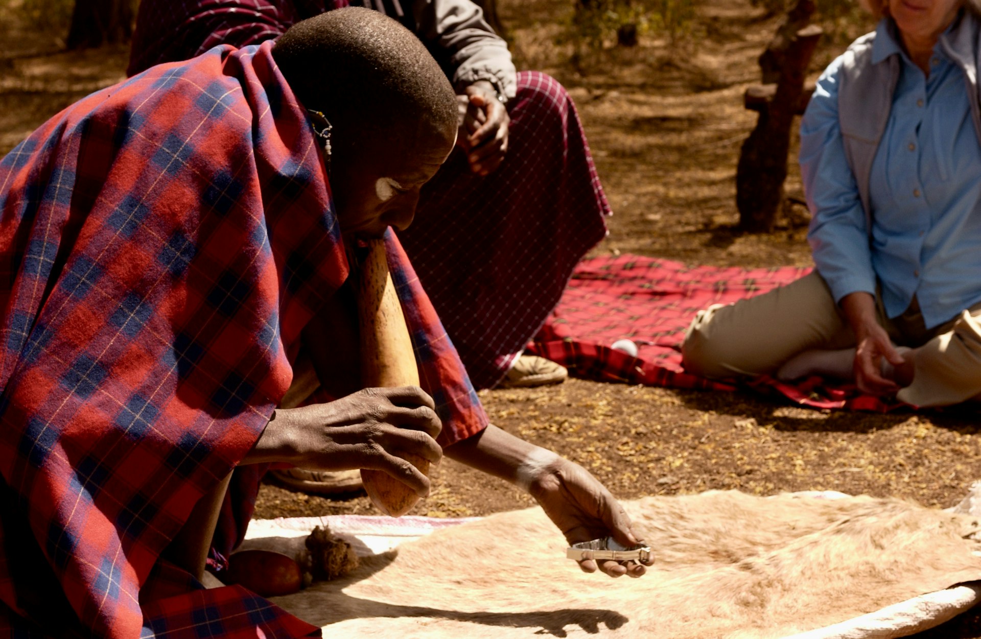 man in red and blue plaid dress shirt sitting on ground